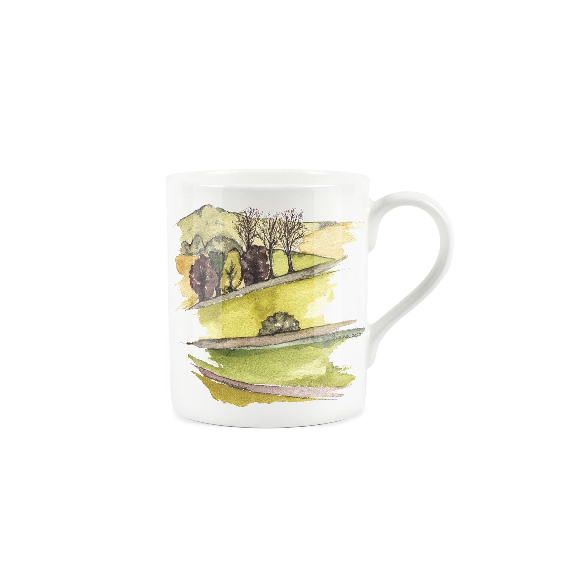 Watercolour depiction of hilly pastoral landscape featuring hedges, fields, and trees on a white bone china mug