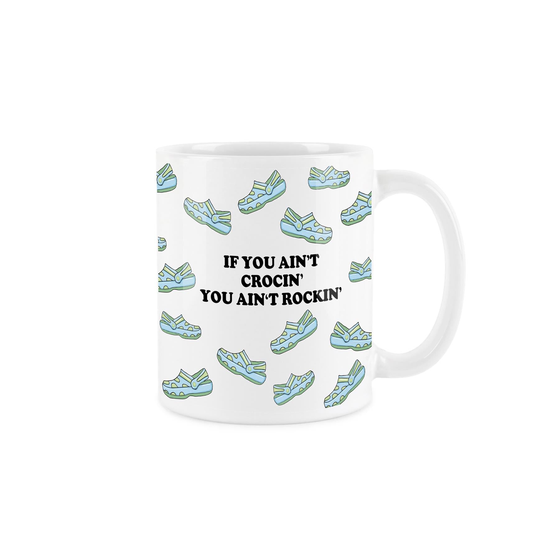 Crocs enthusiast mug: white ceramic covered in blue & green shoes with 'If you ain't rockin' you ain't crocin'.' 325ml capacity, dishwasher-safe.